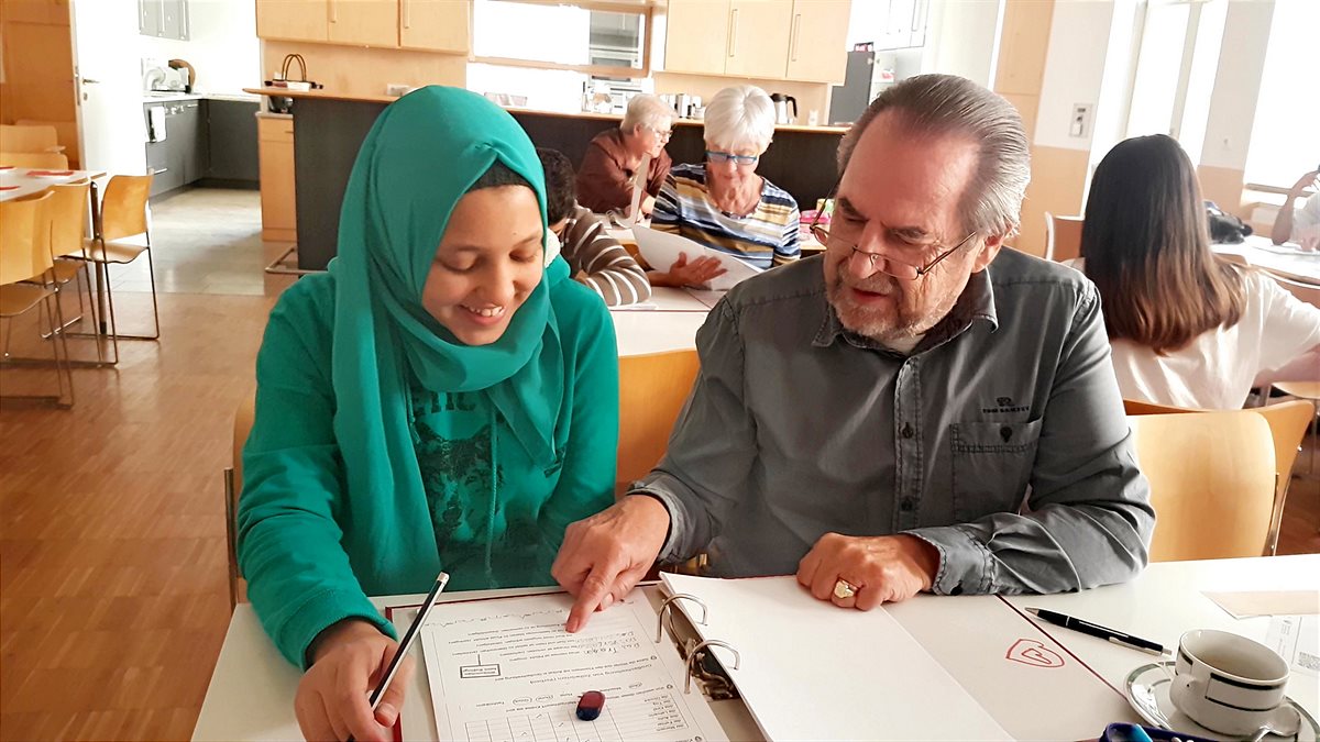Mitarbeiterinnen und Mitarbeiter sowie Freiwillige helfen im Caritas Lerncafè Linz bei den Hausaufgaben und der Vorbereitung auf Tests und Schularbeiten. 